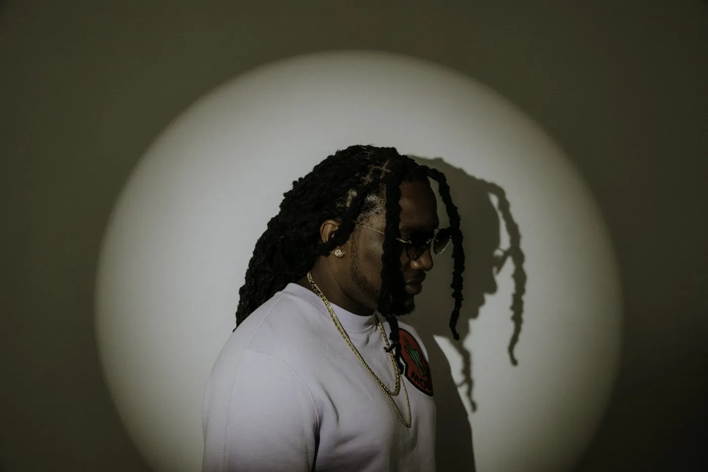 Artiest met dreadlocks voor een spotlight, in silhouet